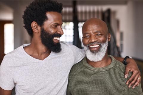 Father and Son standing close together and smiling at each other.