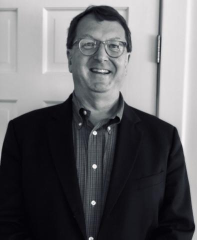 Black and white photo of a man standing in front of a door