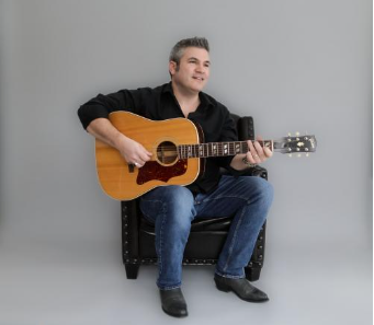 a man playing a guitar against a gray background