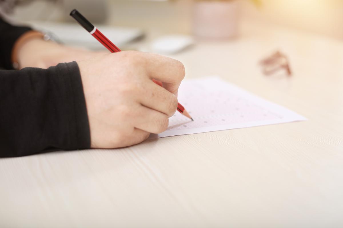 Hand holding pencil with test paper