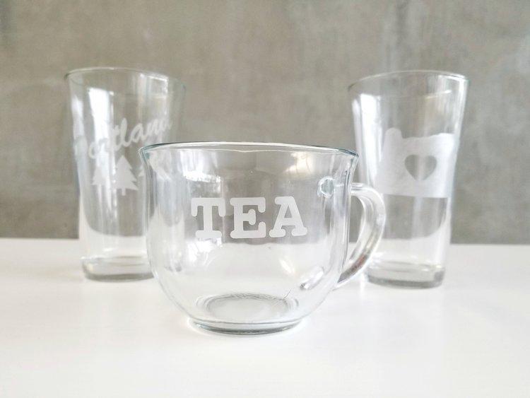 three glasses with etched words and designs