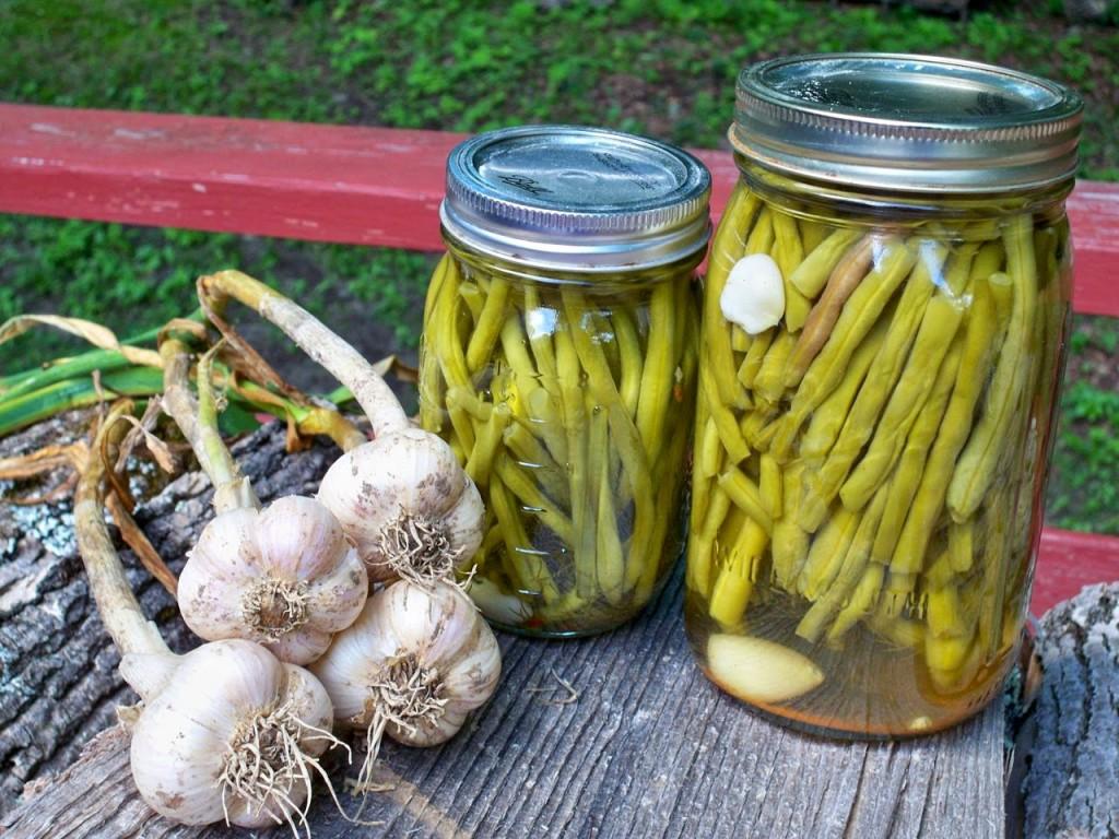 raw garlic and two jars of pickled beans on table