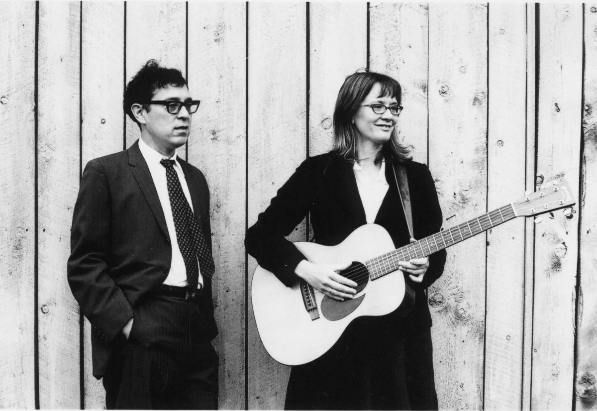 Black and white photo of man and women with guitar standing 