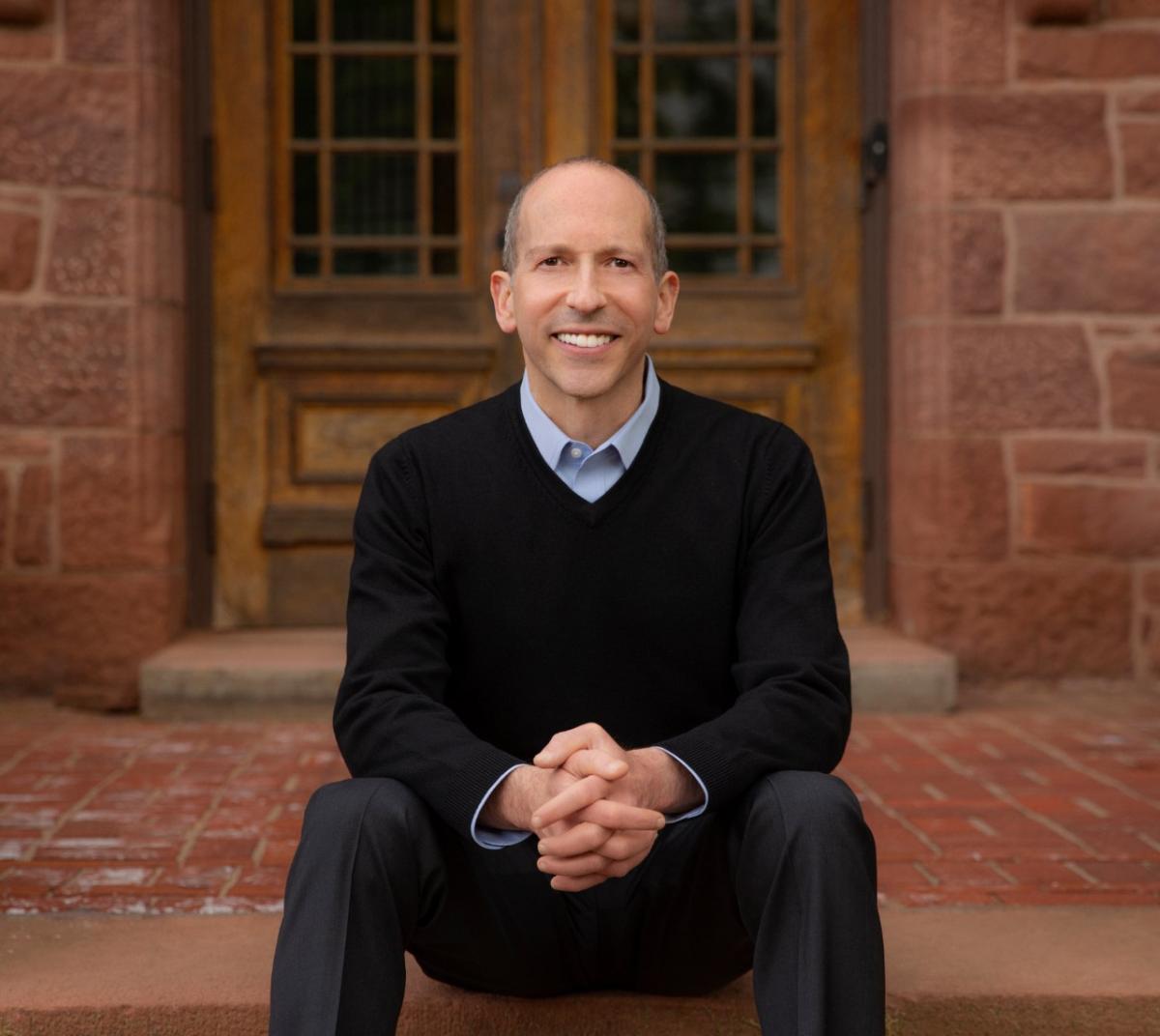 author sitting on step in front of building