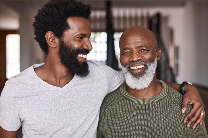 Father and son stand close together and are smiling