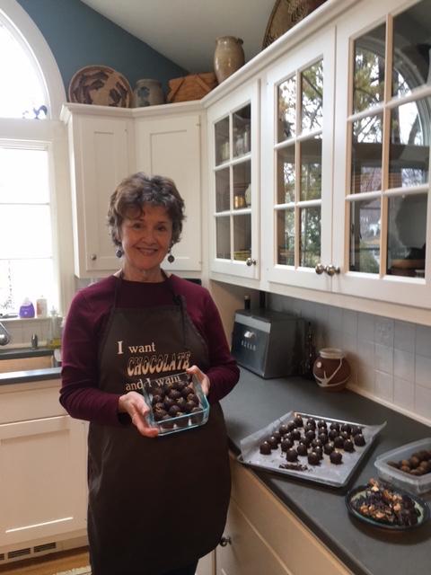 A woman holding chocolates in a glass container against a background of a kitchen 