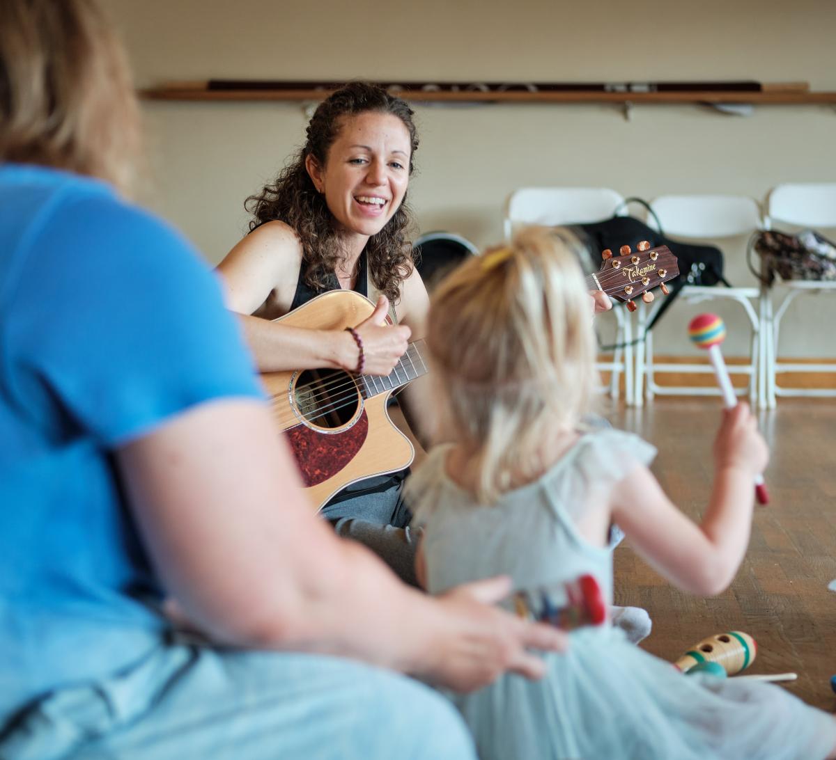 woman playing guitar to children