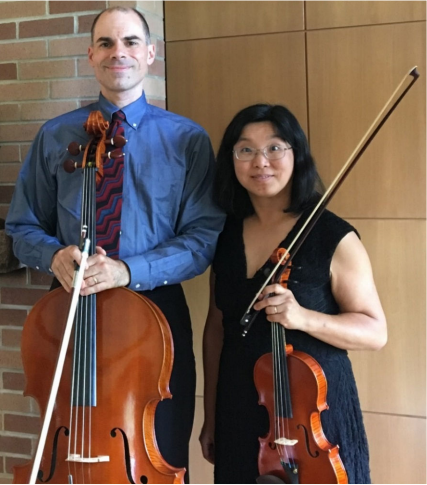 Randy and Millie Calistri-Yeh standing next to each other holding wooden violins